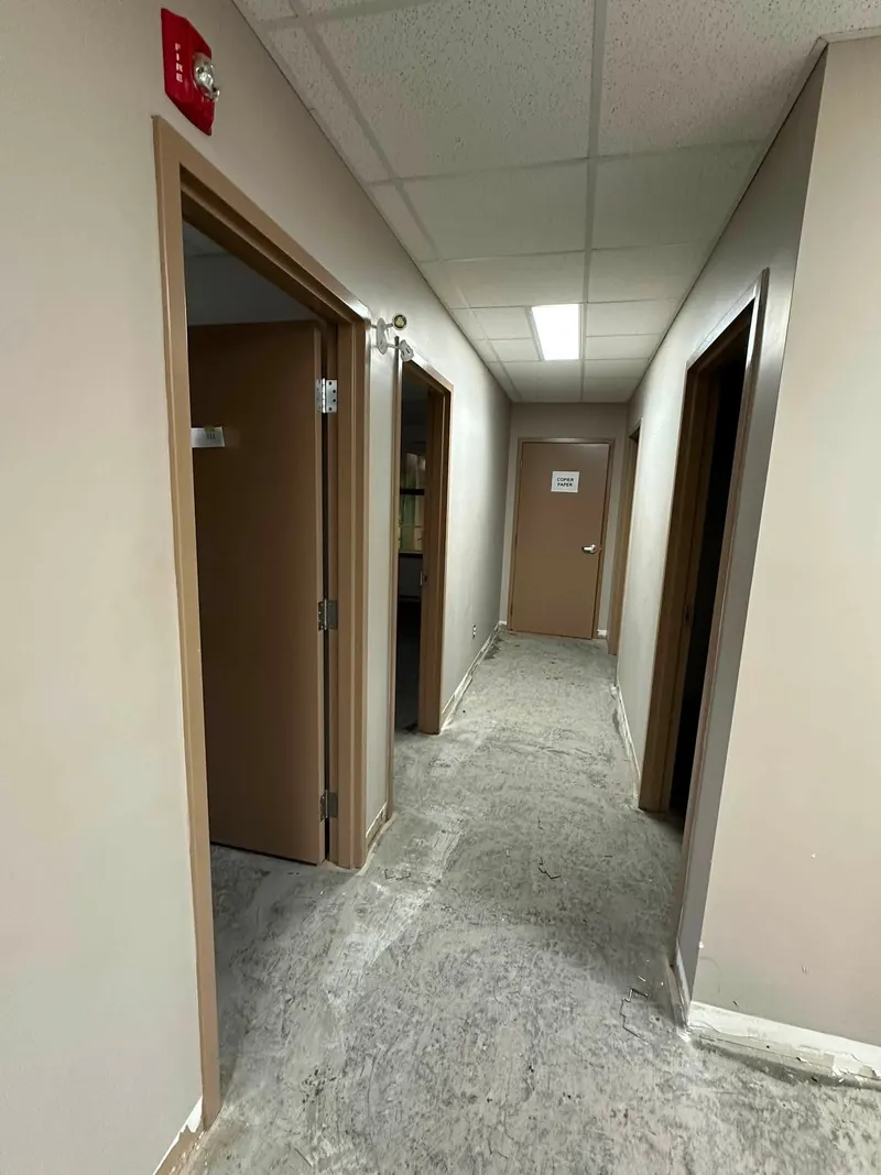 Corridor with beige walls and wood-framed doors, floor not yet finished