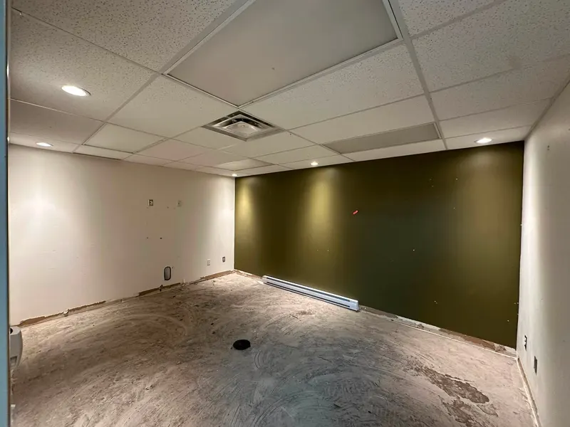 Office room with a dark charcoal accent wall, white walls and a wood-look floor